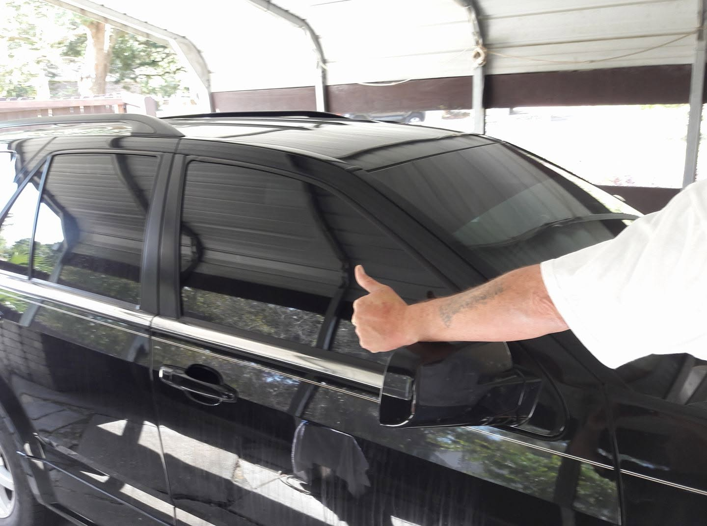 Black SUV with heavily tinted windows and a happy customer giving a thumbs up