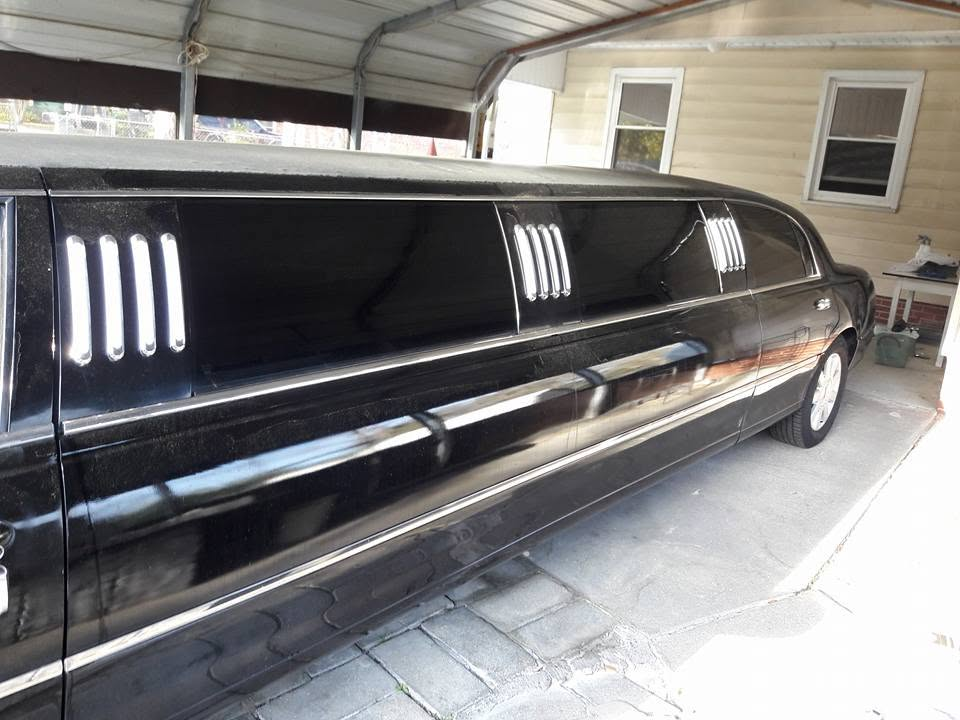 Black limousine with glossy dark tinted windows under a carport